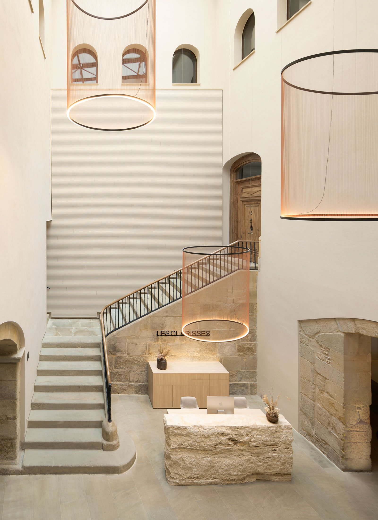 Boutique hotel lobby with heritage stone walls and suspended ring luminaires