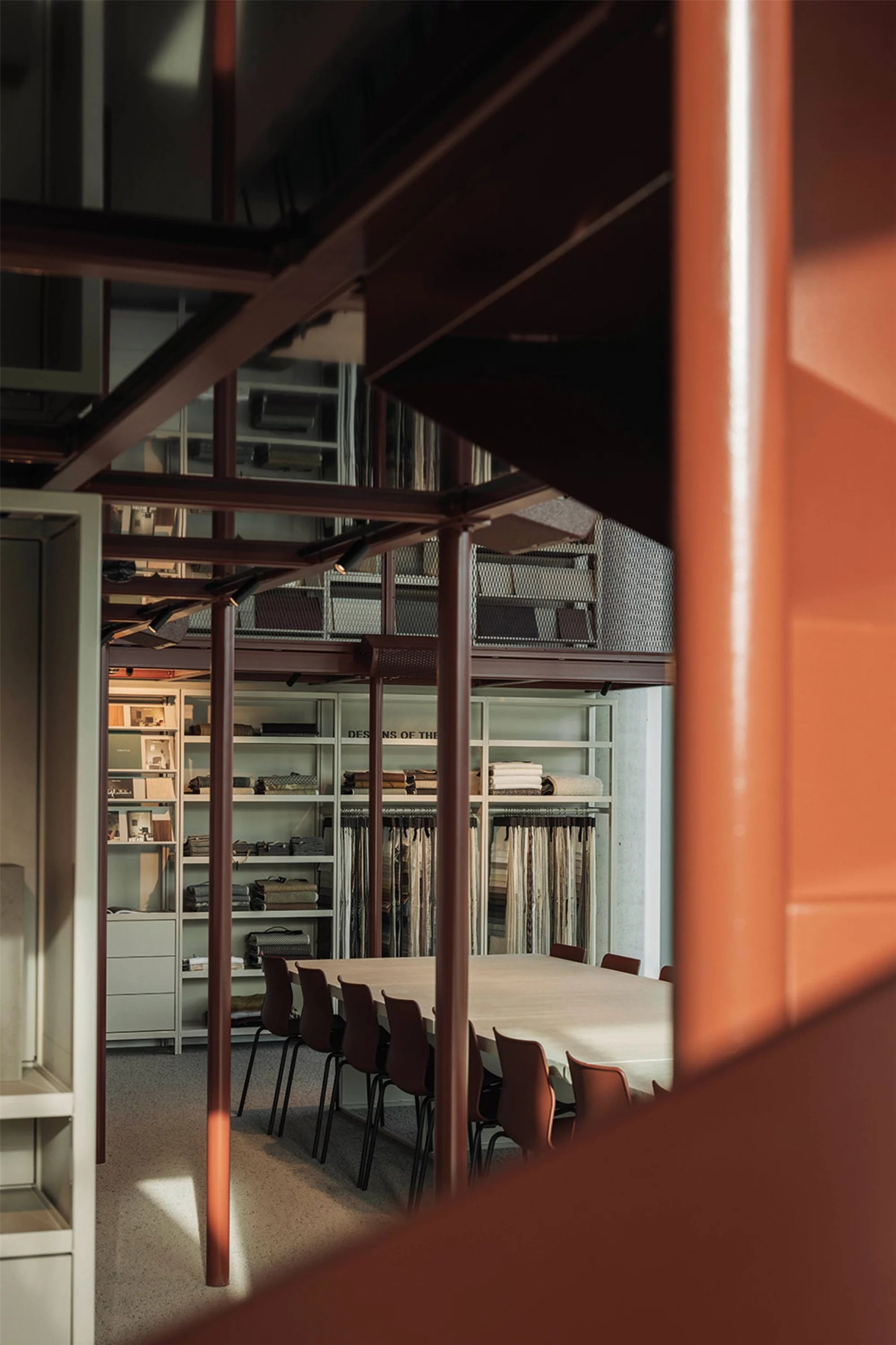Design studio material library with warm accent lighting on oxide-red steel structure