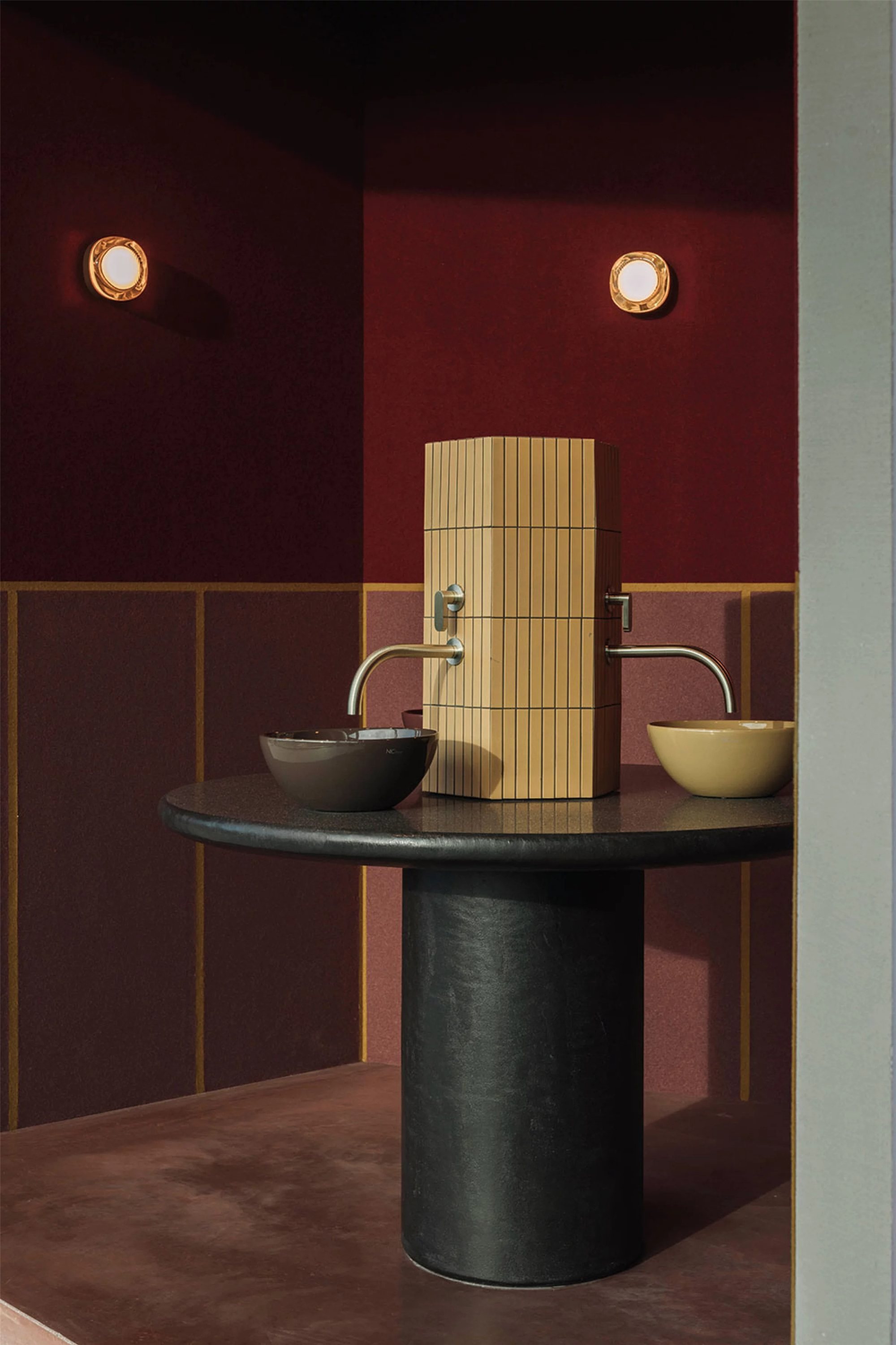 Hotel powder room in burgundy tones with two round wall lights