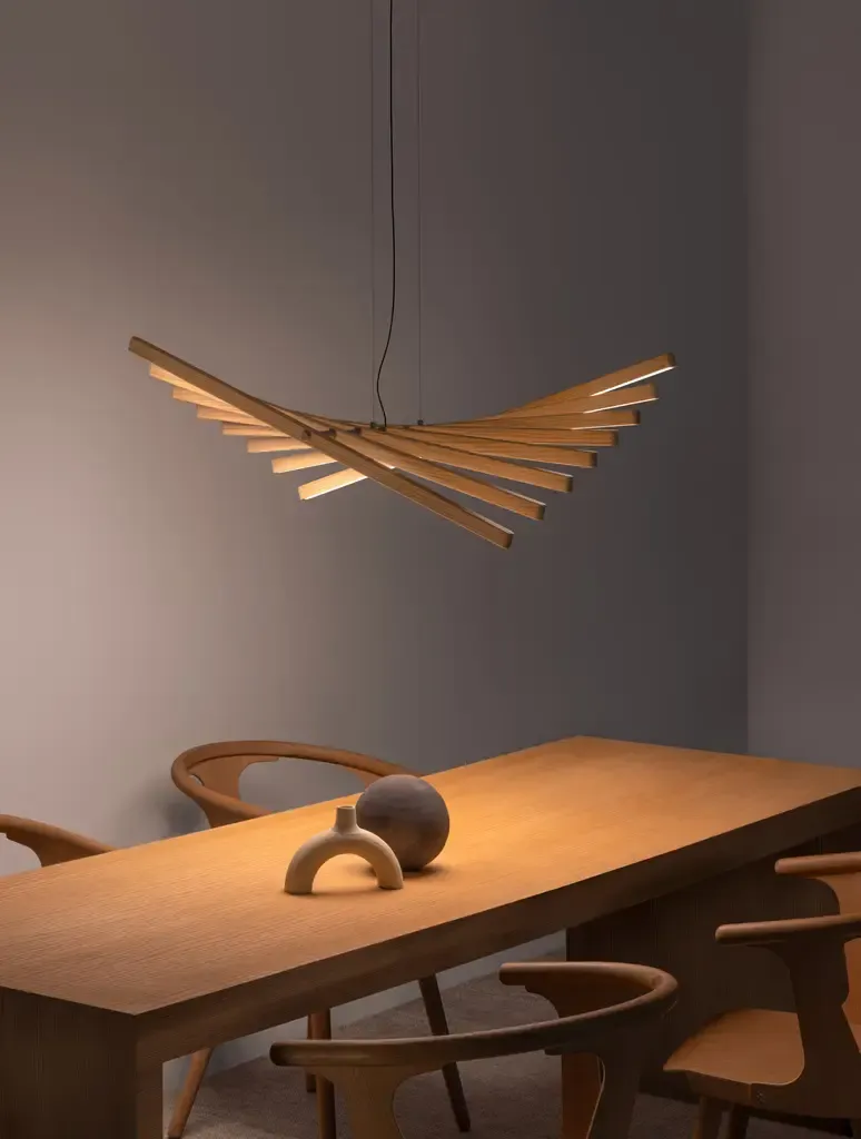 Dining table under a fanned timber pendant in warm light
