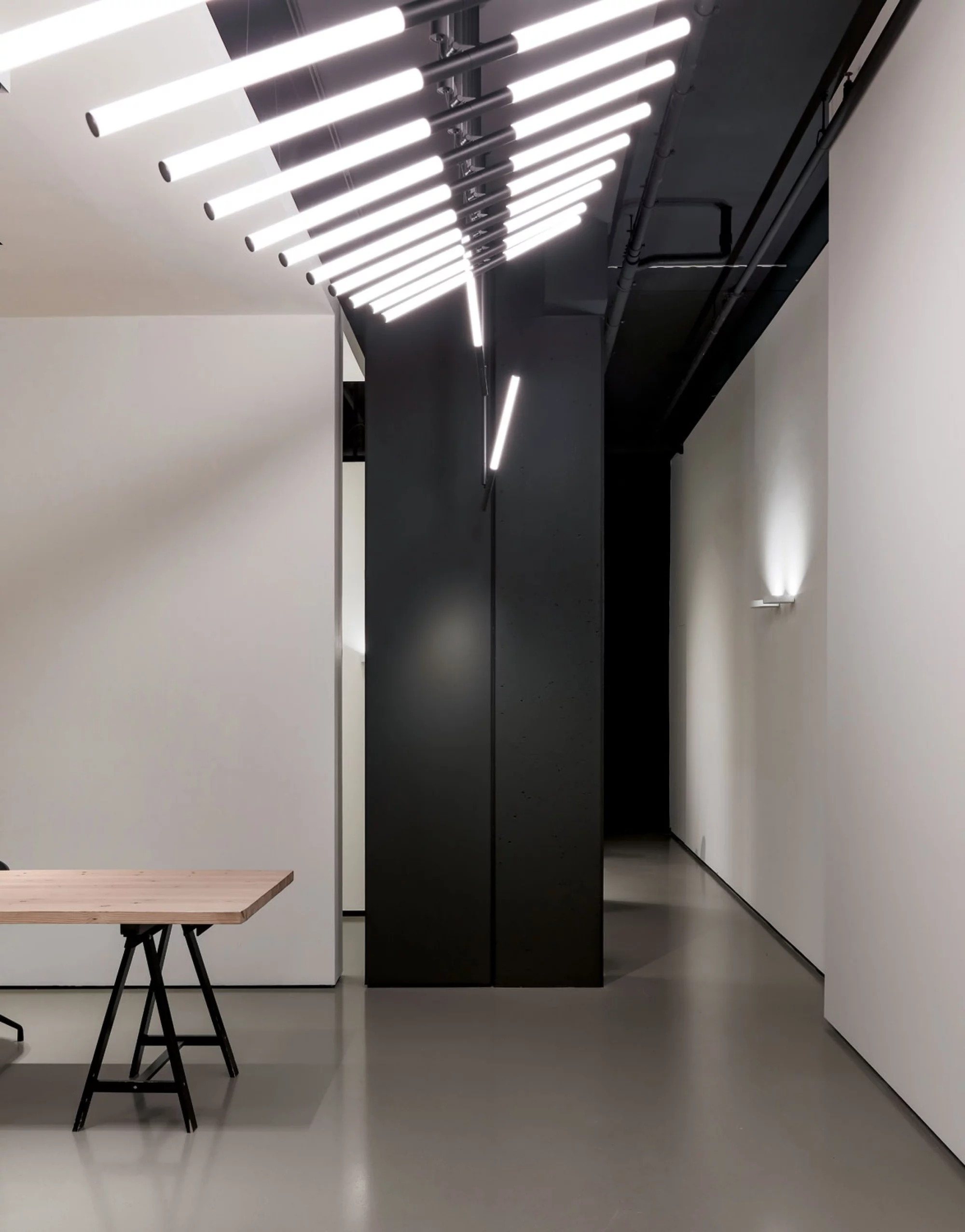 Retail space with a fanned installation of luminous tubes on a dark ceiling