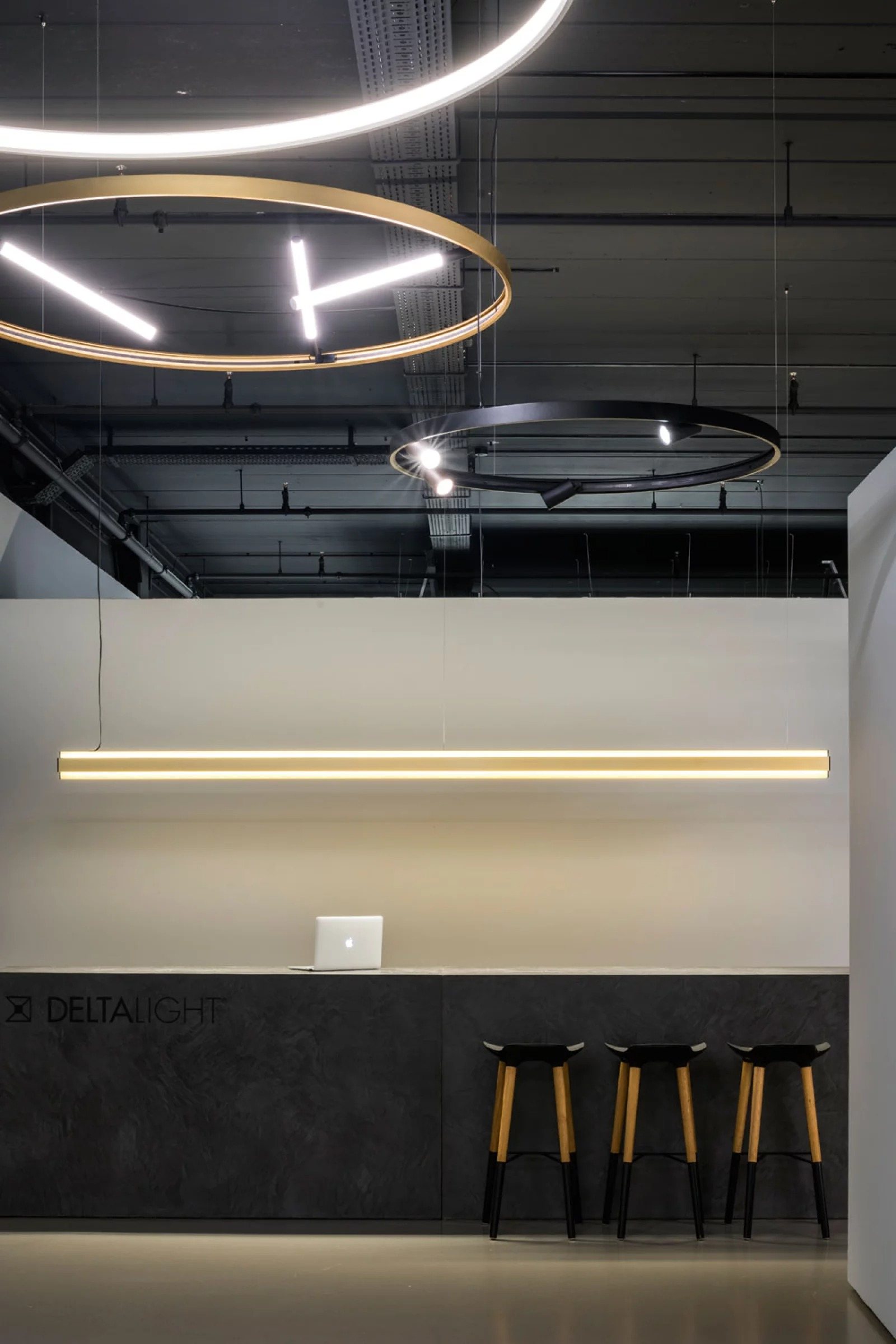 Showroom reception with layered ring pendants in brass and black